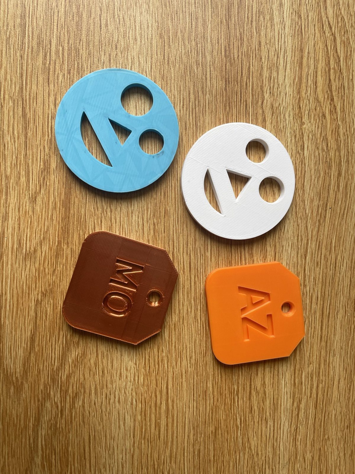 Four printed tags: two round StarStack logo keyrings in light blue and white, and two bag tags stamped MO and AZ.